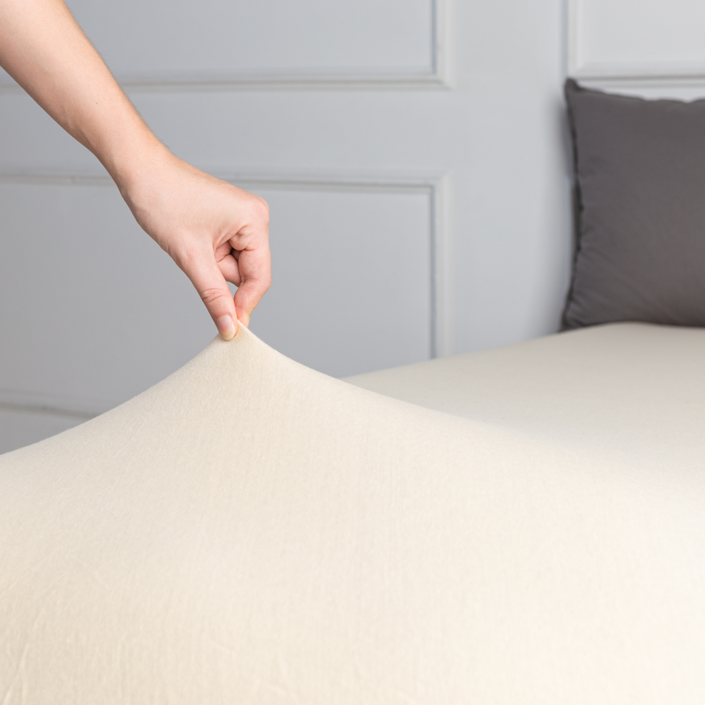 Jersey fitted sheet “Sand”. Fitted sheets 180x200, 90x200 cm, 140x200 cm, 160x200 cm, 180x200 cm, 200x220 cm. Close-up of the corner of a sand-colored fitted sheet.